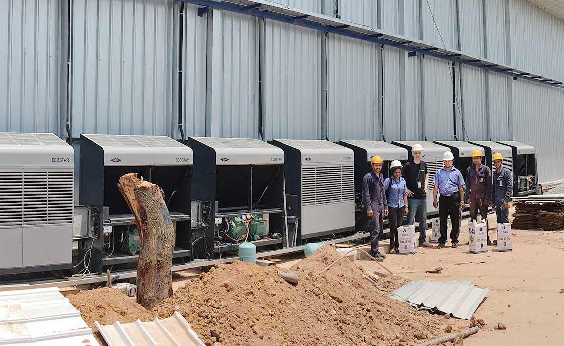 Project employees standing in front of the compressors with a large storage unit in the background